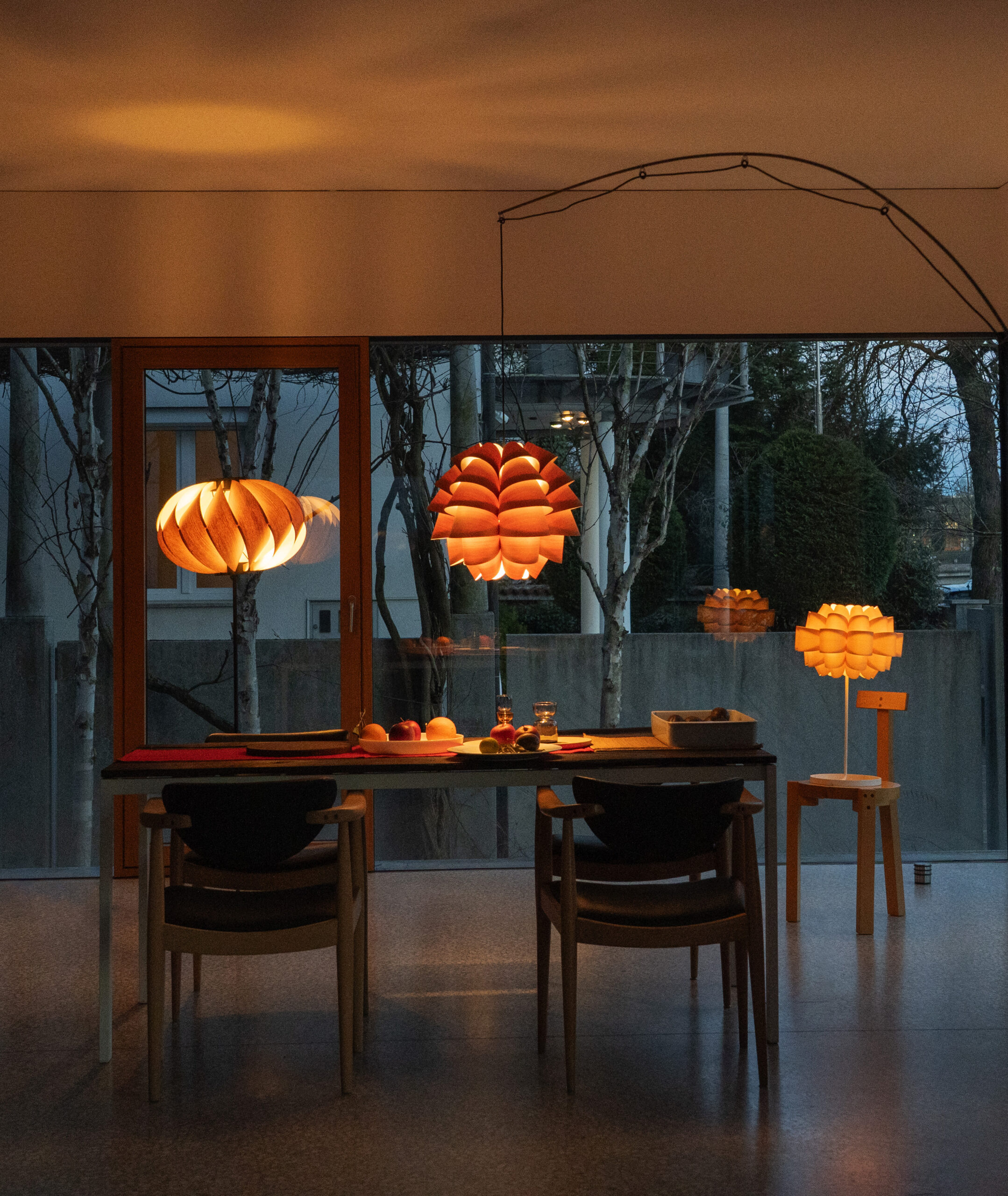Sence pendant, table, and floor lamps around a luxurious dining table at dusk